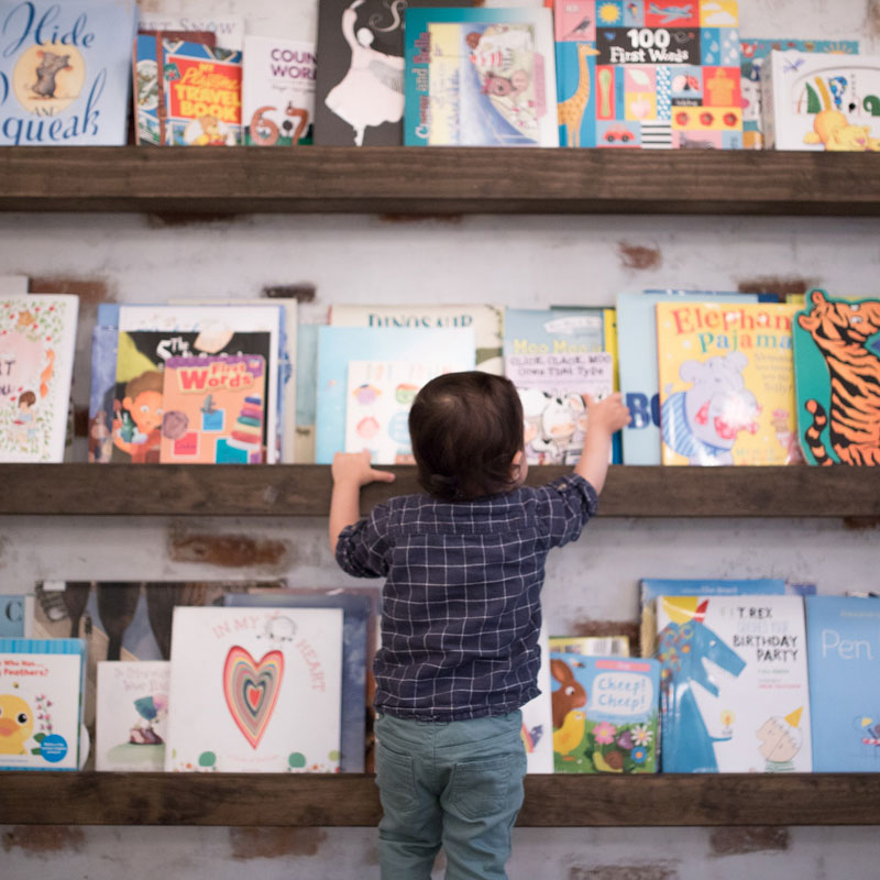 Child selecting a book from a wall of children's books