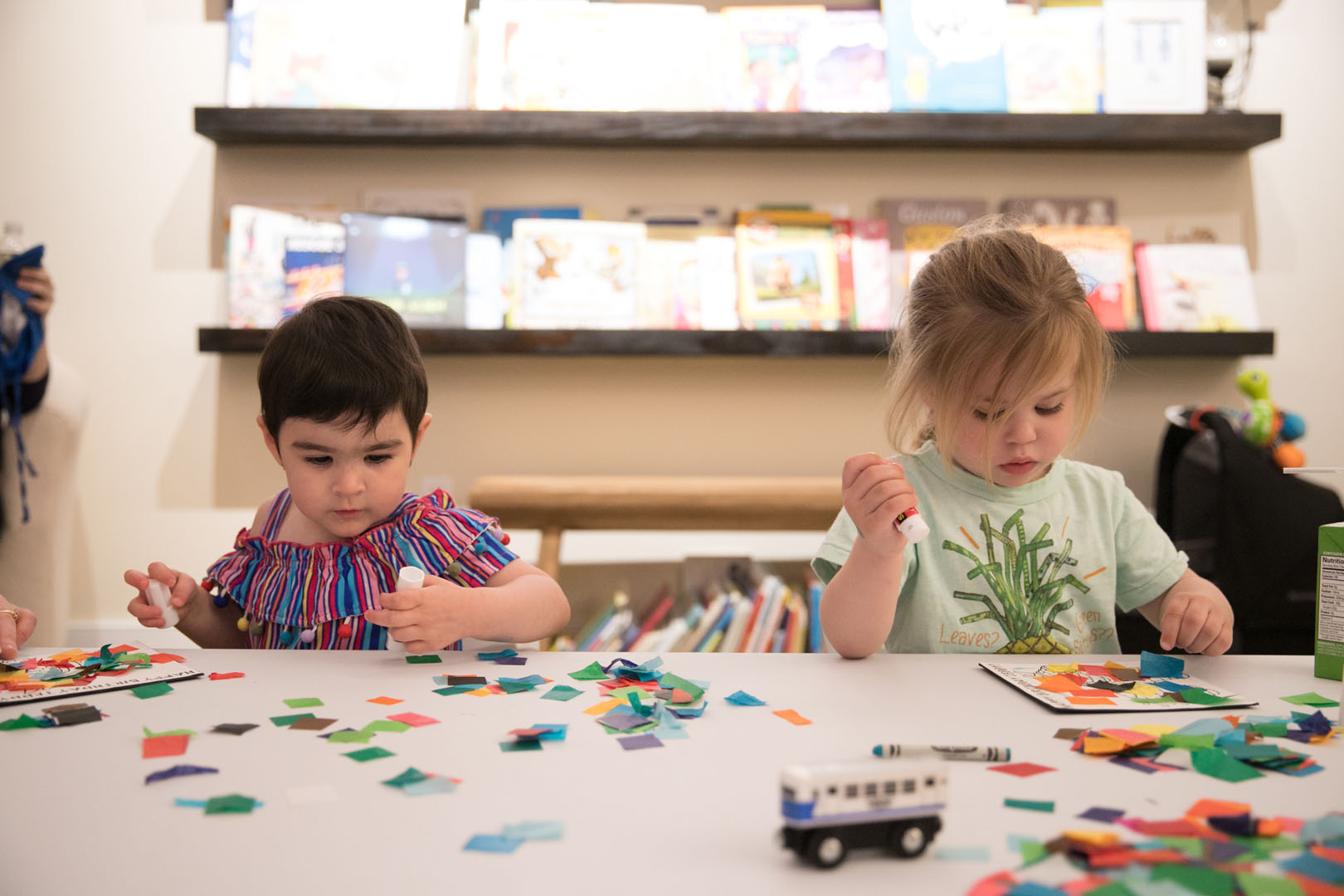Two young girl students working o crafts involving different colored paper circles