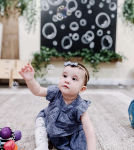 A baby reaching towards the sky to pop a bubble 