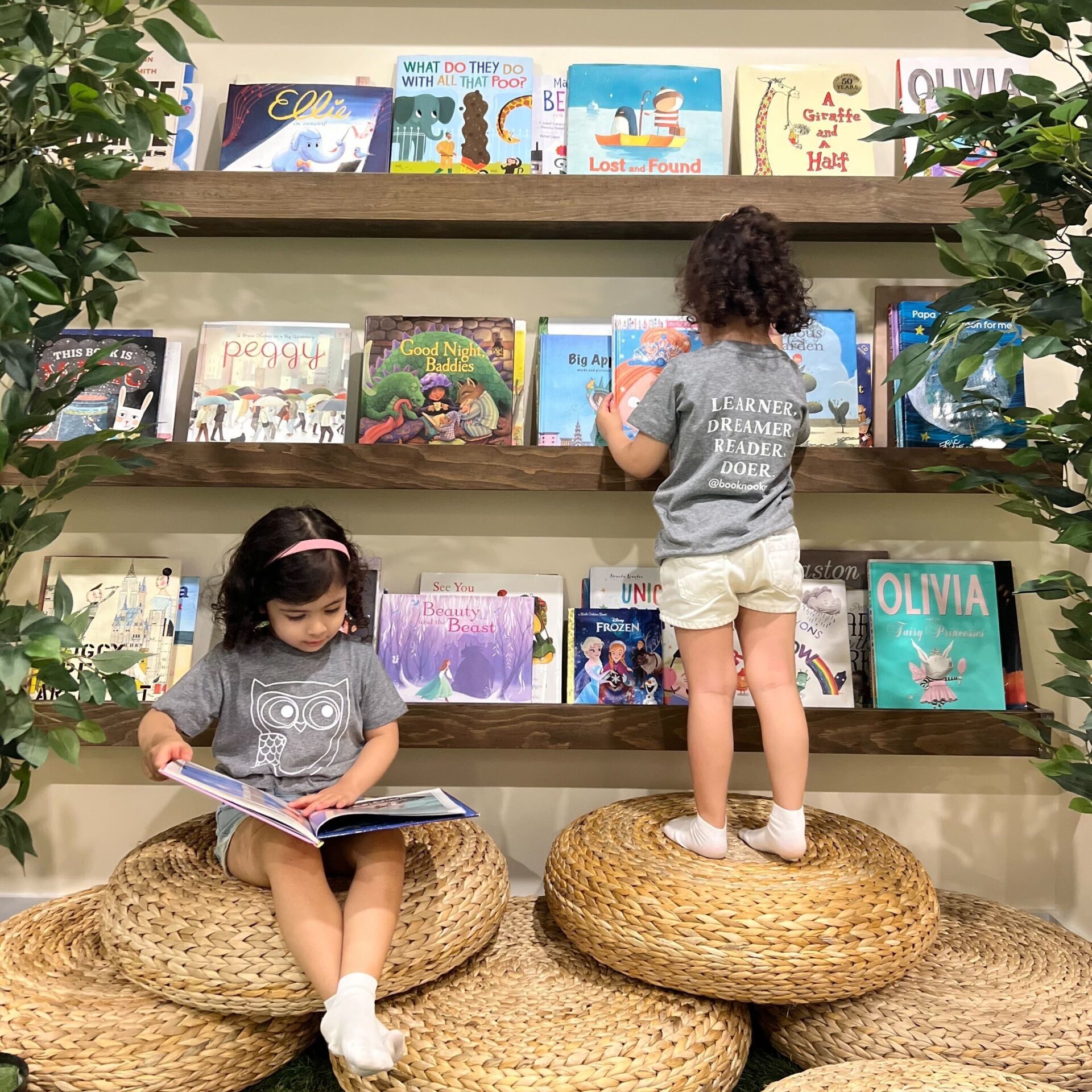 Two young girls selecting books from the reading section at Wise Wonder