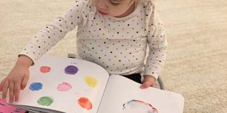 Young girl reading a picture book, the current page has colored circles on it